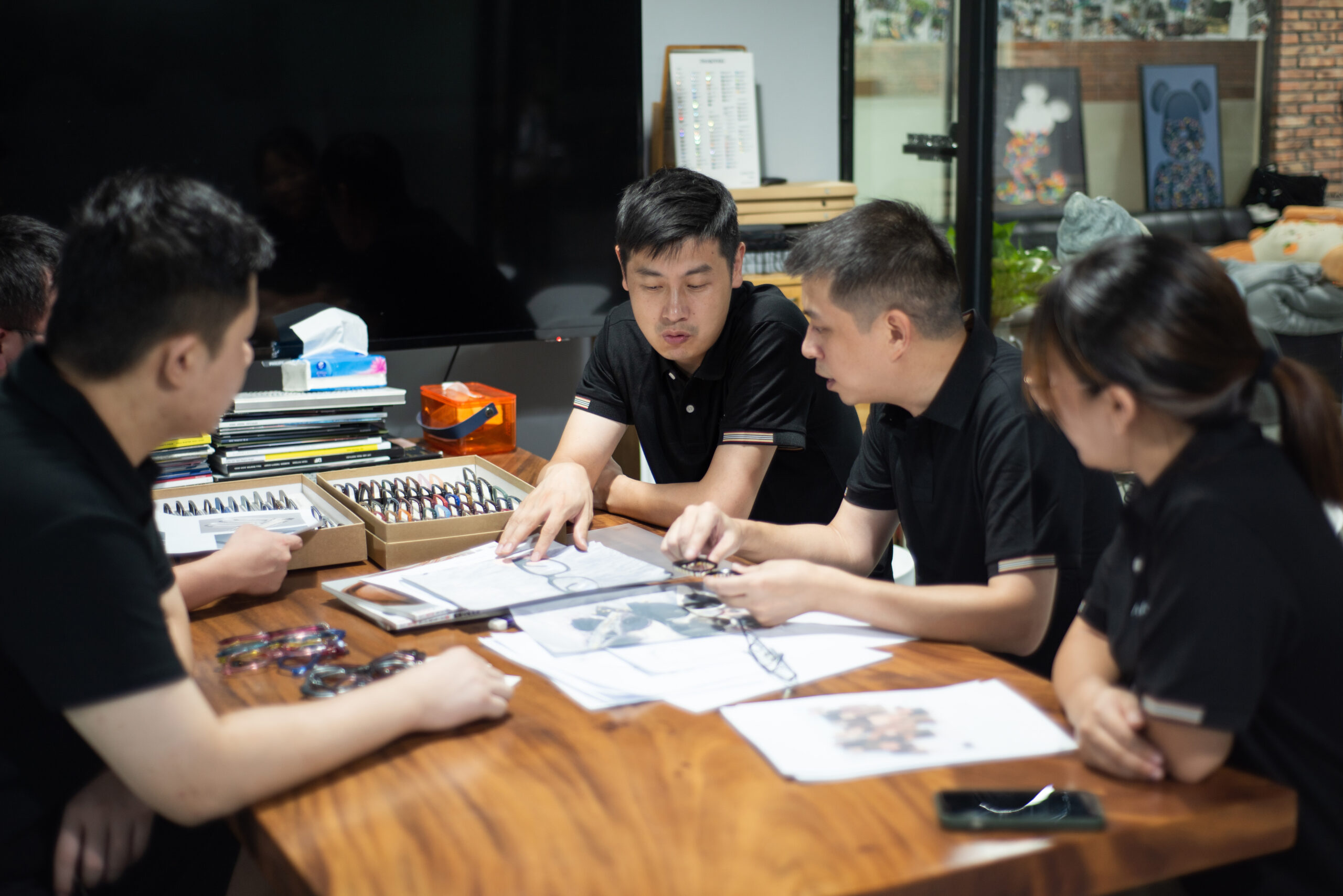 Eyewear development team reviewing frame drawings and samples